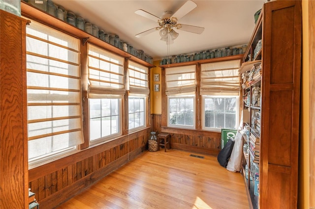 spare room featuring ceiling fan, light wood-type flooring, and wooden walls