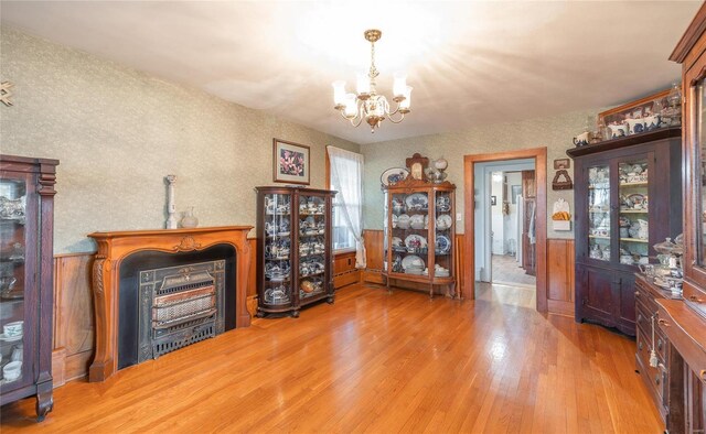 dining room with a chandelier, wood finished floors, and wallpapered walls