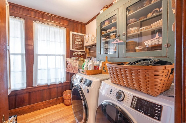 laundry room with washer and dryer, wood walls, ornamental molding, and wood finished floors