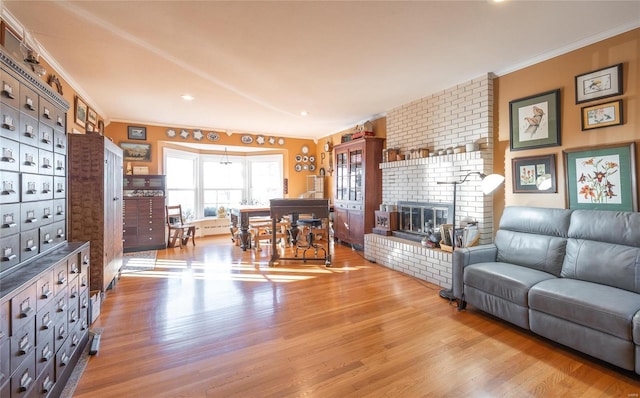 living area featuring ornamental molding, wood finished floors, a brick fireplace, and recessed lighting