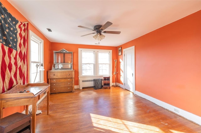 miscellaneous room featuring baseboards, ceiling fan, radiator heating unit, and wood finished floors