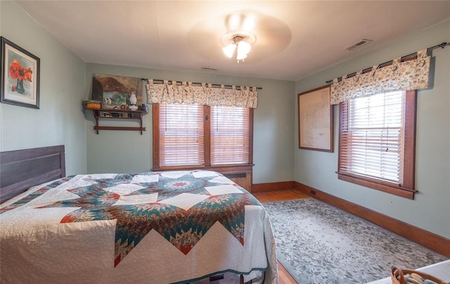 bedroom with wood finished floors, baseboards, and multiple windows