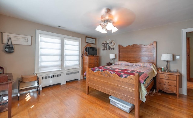 bedroom with radiator, light wood-style floors, and ceiling fan
