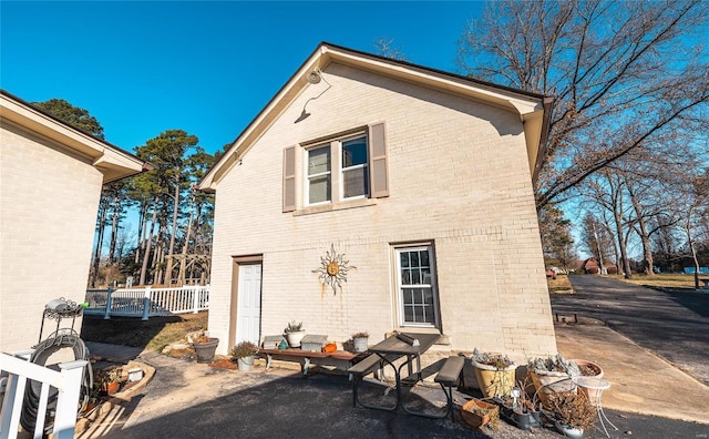 rear view of property featuring brick siding, a patio, and fence