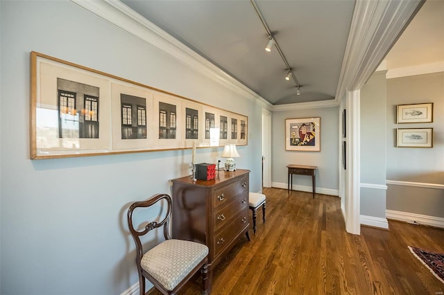 hall with dark wood-type flooring, track lighting, baseboards, and ornamental molding