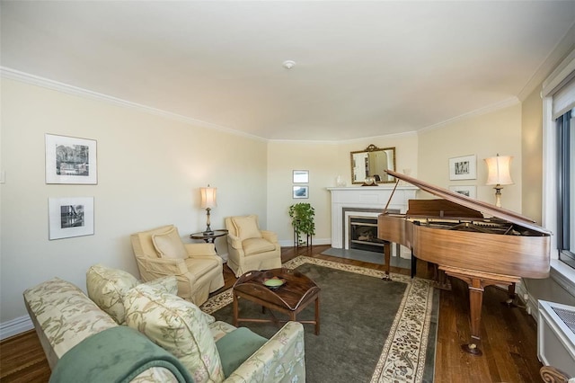 living area with a fireplace with flush hearth, wood finished floors, crown molding, and baseboards
