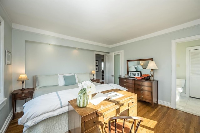 bedroom with wood finished floors, baseboards, and ensuite bathroom