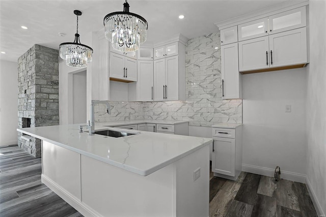 kitchen with a sink, a chandelier, dark wood finished floors, recessed lighting, and glass insert cabinets