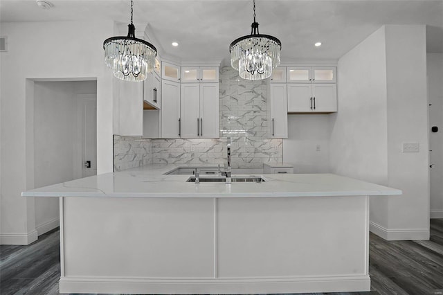 kitchen with a sink, a chandelier, baseboards, dark wood finished floors, and tasteful backsplash