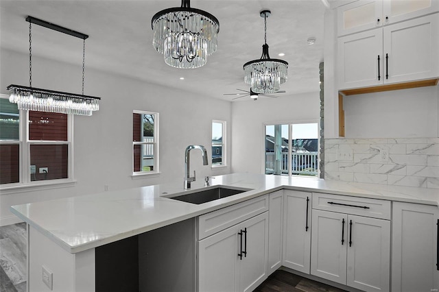 kitchen featuring a chandelier, a sink, dark wood-style floors, a peninsula, and pendant lighting