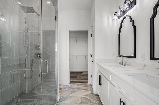 full bathroom with a shower stall, a spacious closet, marble finish flooring, and double vanity
