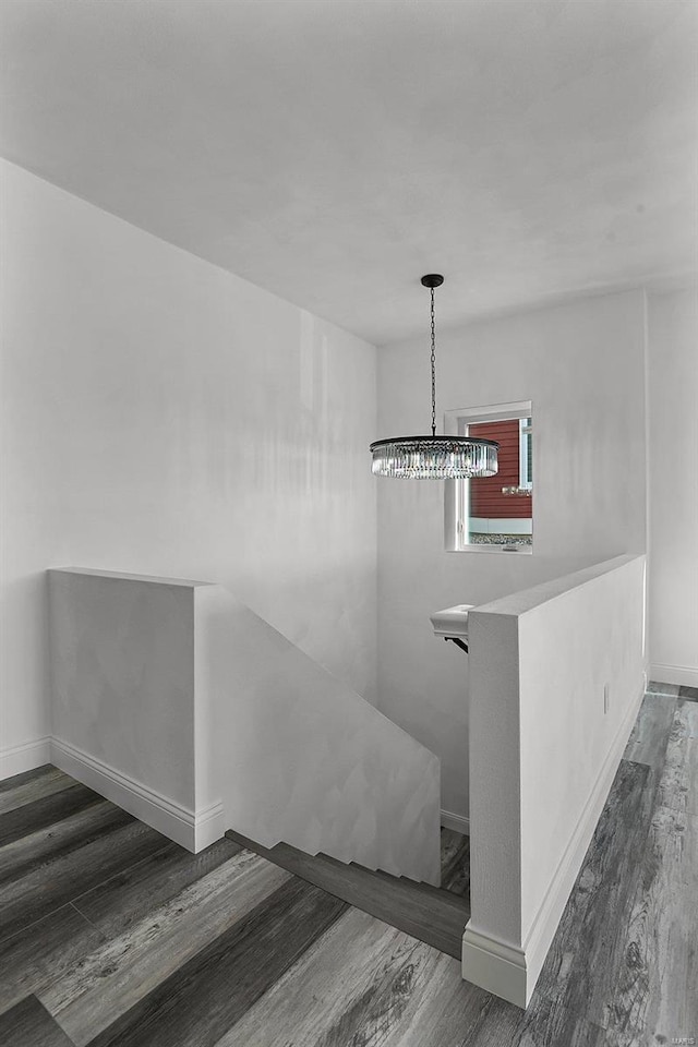 staircase with wood finished floors, baseboards, and a chandelier
