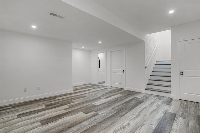 below grade area with wood finished floors, stairs, recessed lighting, and baseboards