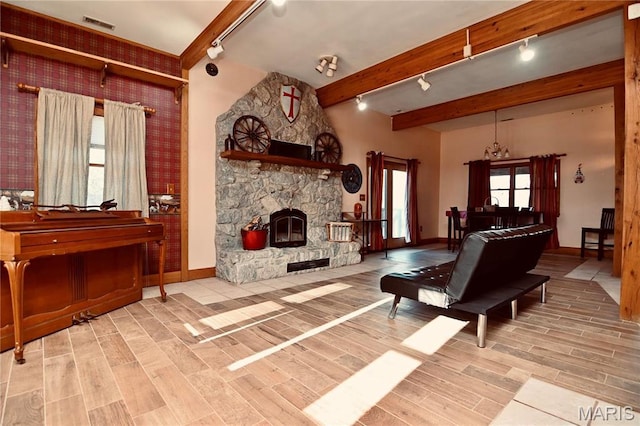 26 Gap Rd, Tunas, MO 65764 - living area featuring rail lighting, baseboards, wood finished floors, beam ceiling, and wallpapered walls
