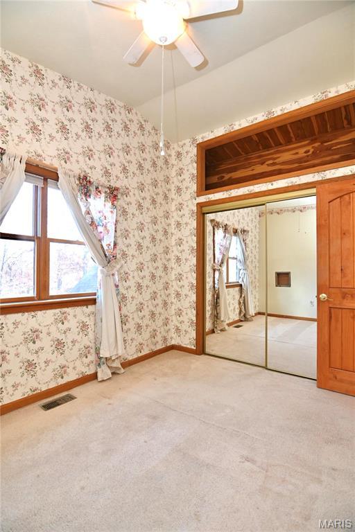 26 Gap Rd, Tunas, MO 65764 - unfurnished bedroom featuring light colored carpet, wallpapered walls, baseboards, ceiling fan, and a closet