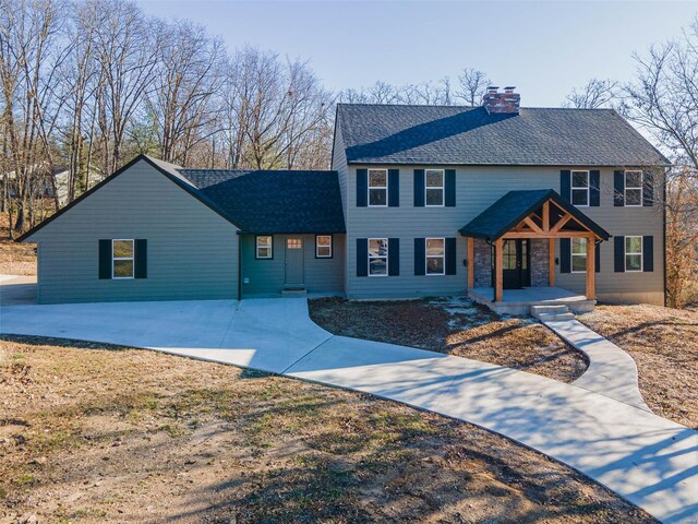 view of front of home featuring covered porch, a chimney, and a shingled roof