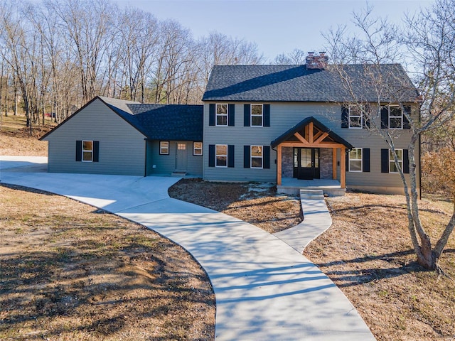view of front of property with covered porch, a shingled roof, and a chimney