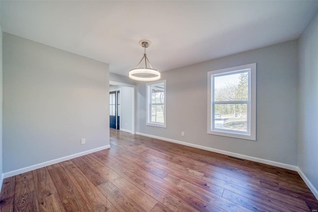 unfurnished dining area with wood-type flooring and baseboards
