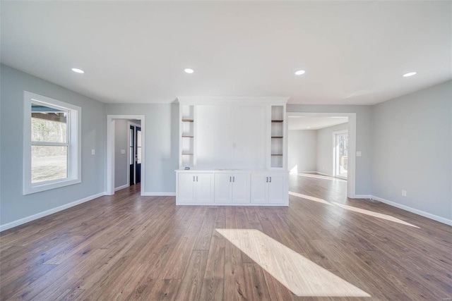 unfurnished living room with plenty of natural light, wood finished floors, baseboards, and recessed lighting