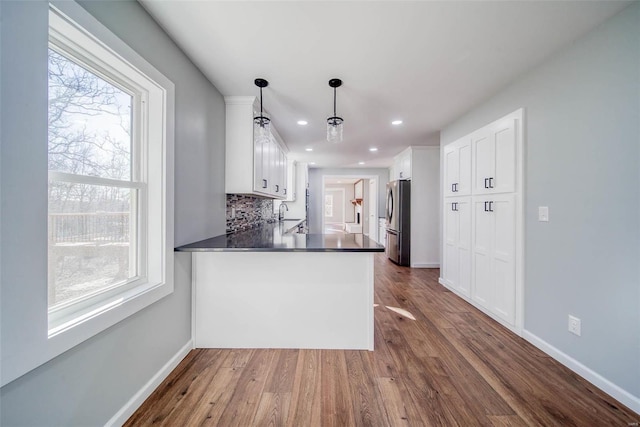 kitchen with freestanding refrigerator, dark countertops, healthy amount of natural light, white cabinets, and recessed lighting