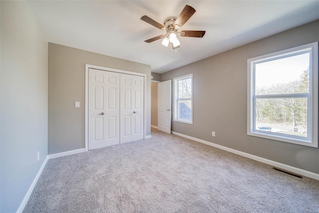 unfurnished bedroom featuring baseboards, carpet flooring, and a closet