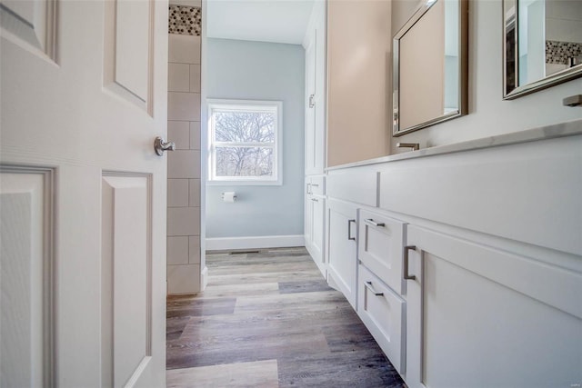 full bath with wood finished floors, vanity, and baseboards