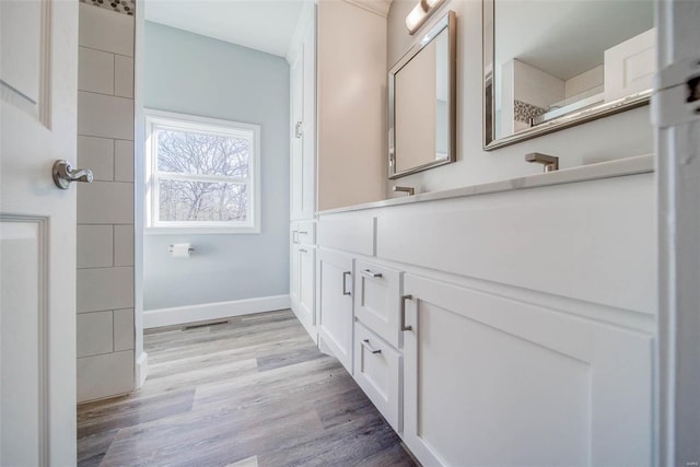 bathroom featuring wood finished floors, baseboards, and vanity