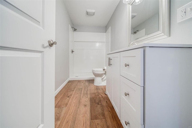 bathroom with a shower, toilet, wood finished floors, and vanity