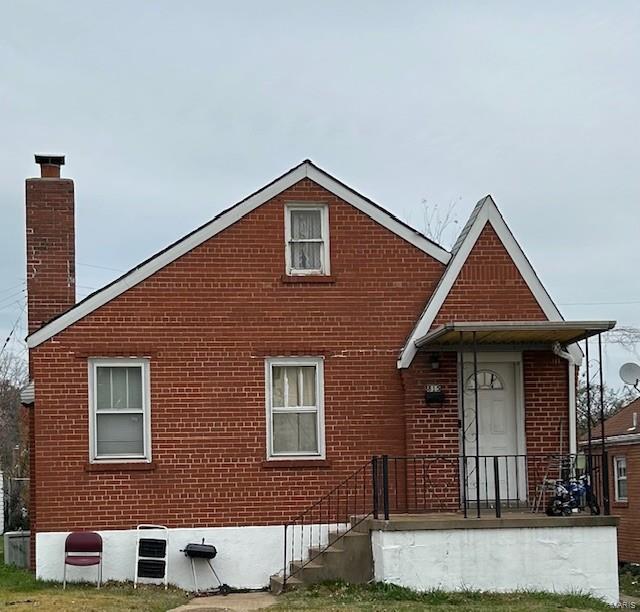 view of front of home with brick siding and a chimney