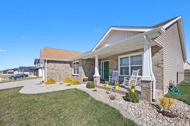 single story home with a porch, a front lawn, board and batten siding, and brick siding