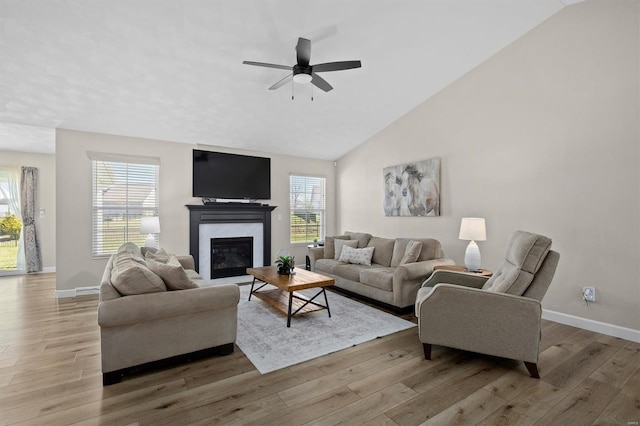 living area with healthy amount of natural light, light wood-type flooring, baseboards, and high vaulted ceiling