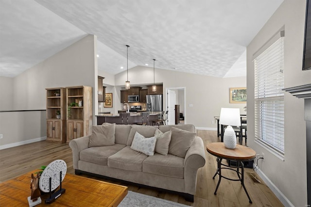 living room with wood finished floors, vaulted ceiling, and baseboards