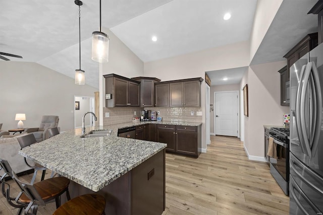 kitchen with stainless steel appliances, open floor plan, a peninsula, a sink, and dark brown cabinets