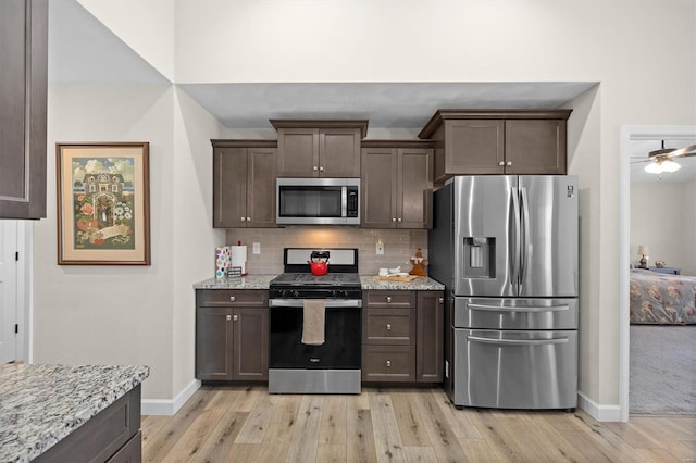 kitchen with stainless steel appliances, dark brown cabinetry, baseboards, and light wood-style floors