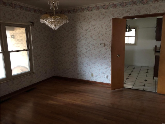 unfurnished dining area featuring wood finished floors, a chandelier, baseboards, and wallpapered walls