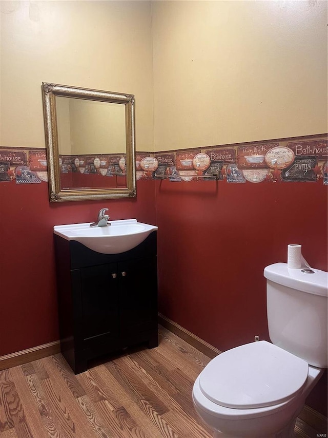 bathroom with toilet, wood finished floors, and vanity