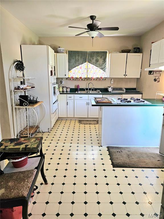 104 Emerling Dr, Saint Louis, MO 63121 - kitchen featuring light flooring, dark countertops, a sink, white cabinetry, and a ceiling fan