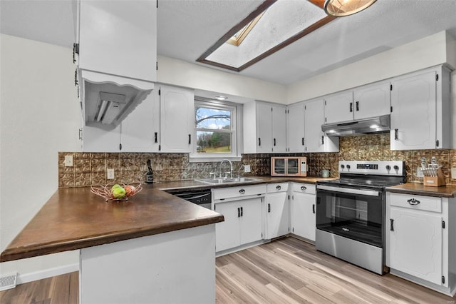 kitchen featuring stainless steel range with electric cooktop, under cabinet range hood, a sink, dark countertops, and a peninsula