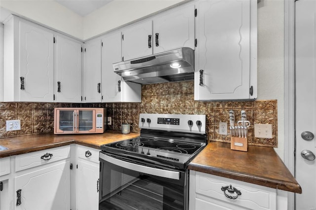 kitchen with range with electric stovetop, under cabinet range hood, tasteful backsplash, and dark countertops