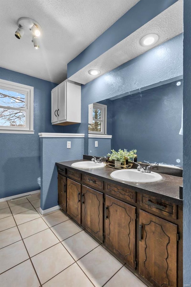 full bathroom with plenty of natural light, tile patterned flooring, double vanity, a textured ceiling, and toilet