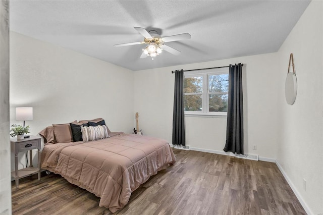 bedroom featuring wood finished floors, baseboards, a ceiling fan, and a textured ceiling