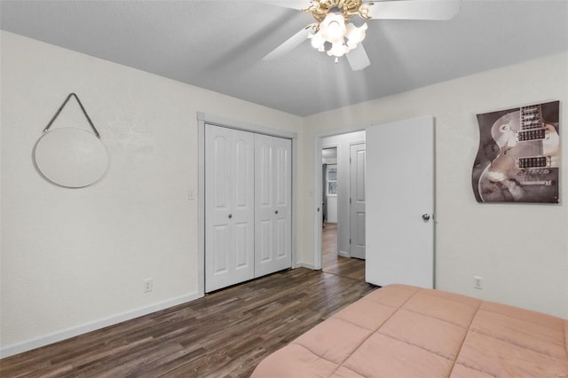 bedroom featuring dark wood-style flooring, a closet, baseboards, and a ceiling fan