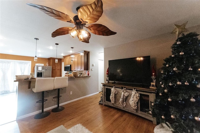 living room with wood finished floors, a ceiling fan, and baseboards