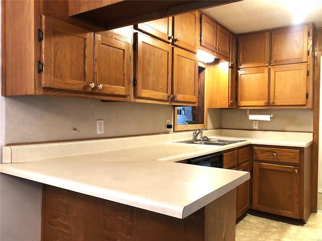 kitchen with a sink, brown cabinetry, light countertops, and a peninsula