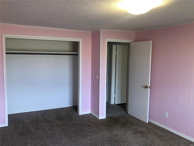 unfurnished bedroom featuring dark colored carpet, crown molding, a closet, and a textured ceiling
