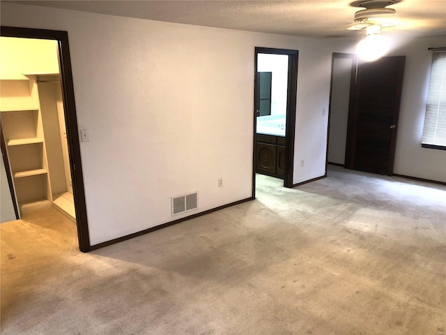 spare room featuring light carpet, a ceiling fan, and baseboards