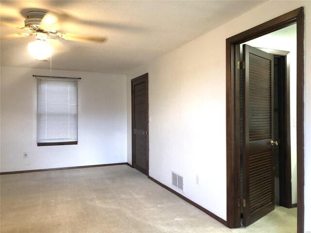 empty room with carpet flooring, ceiling fan, and baseboards