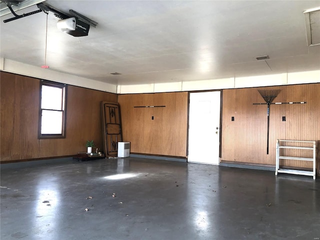 garage with a garage door opener and wooden walls