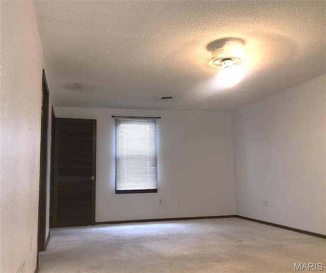 1210 N Prairie, Bloomfield, MO 63825 - spare room featuring a textured ceiling, light carpet, and baseboards