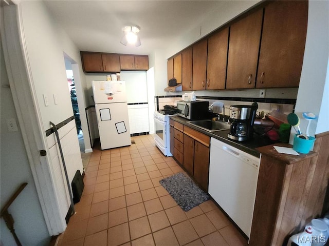 1238 Hoyt Dr, Saint Louis, MO 63137 - kitchen featuring white appliances, dark countertops, a sink, and light tile patterned floors